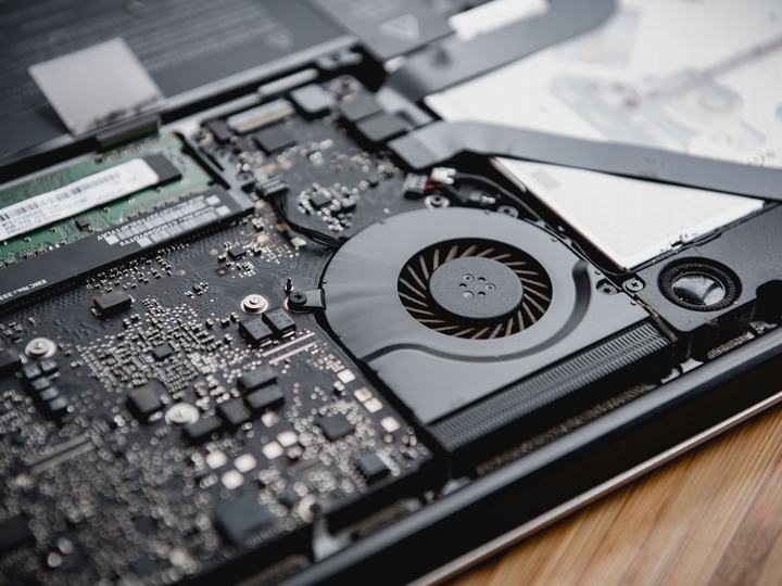 Laptop abierto mostrando sus componentes internos: ventilador, memoria y placa base
